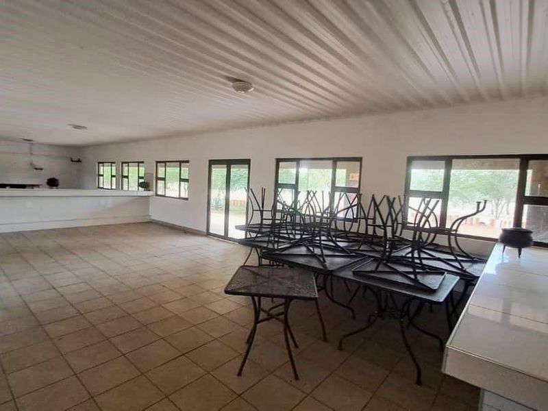 Spacious open-plan area featuring tiled flooring, a built-in bar counter, and large aluminium-framed windows providing ample natural light.
