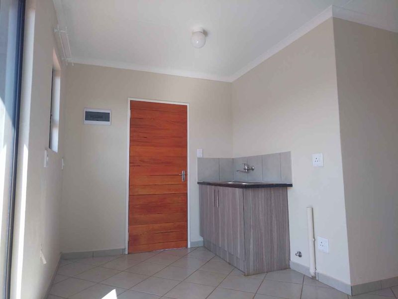 A clean and functional scullery area featuring built-in cabinetry, a sink, and tiled flooring, providing a practical utility space.