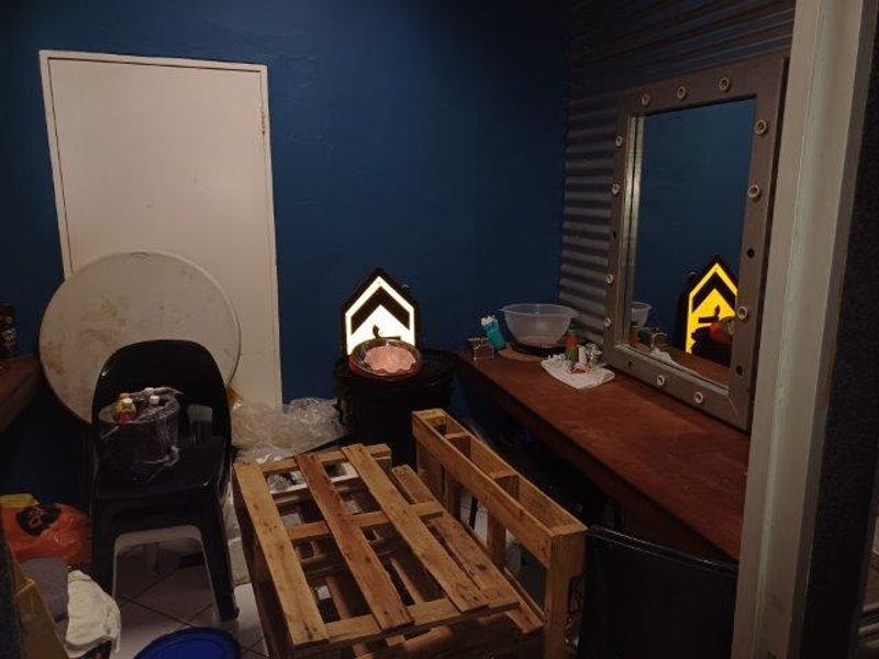 A small office or utility space featuring a built-in vanity mirror, tiled flooring, and corrugated metal wall accents.