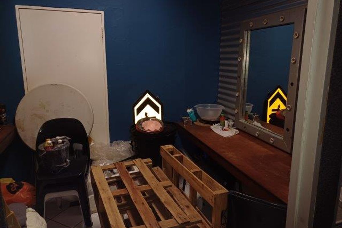 A small office or utility space featuring a built-in vanity mirror, tiled flooring, and corrugated metal wall accents.