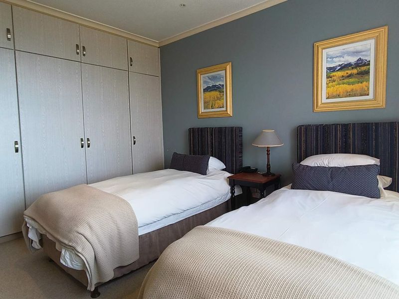 A well-maintained bedroom featuring neutral-toned built-in cupboards and carpeted flooring, providing ample storage and a comfortable living space.