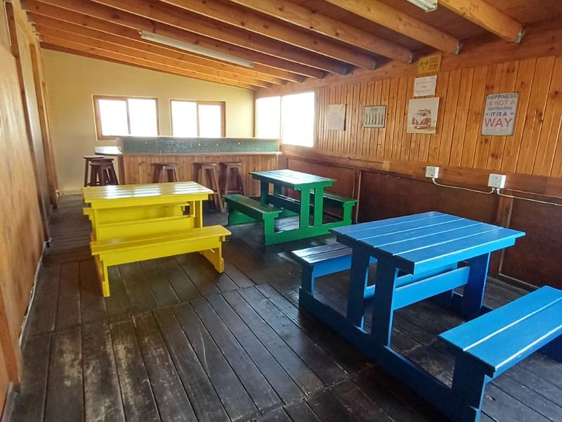 A rustic indoor bar area featuring timber wall paneling, exposed ceiling beams, a built-in bar counter, and wooden flooring.