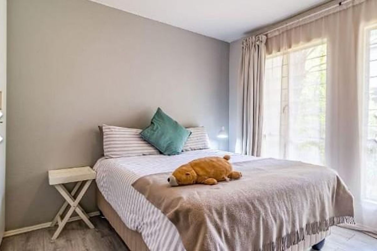 A well-lit bedroom featuring neutral wall tones, laminate flooring, and built-in cupboards with modern hardware.