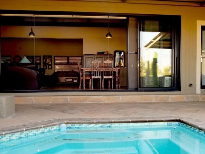 A paved patio area featuring a swimming pool and large sliding glass doors providing seamless access to the indoor living space.