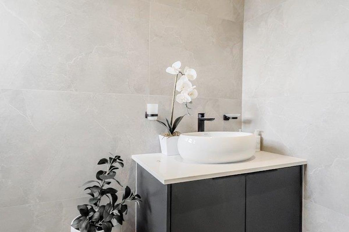 Modern bathroom featuring a wall-mounted vanity unit with a contemporary vessel sink and large-format grey stone-look wall tiles.