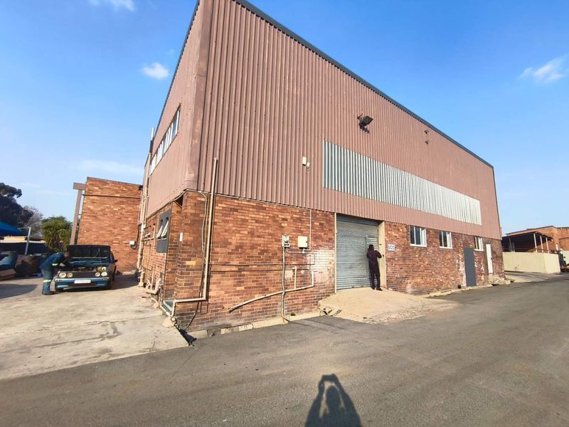 Industrial property featuring a face brick and corrugated metal facade with a roller shutter door and asphalt driveway access.