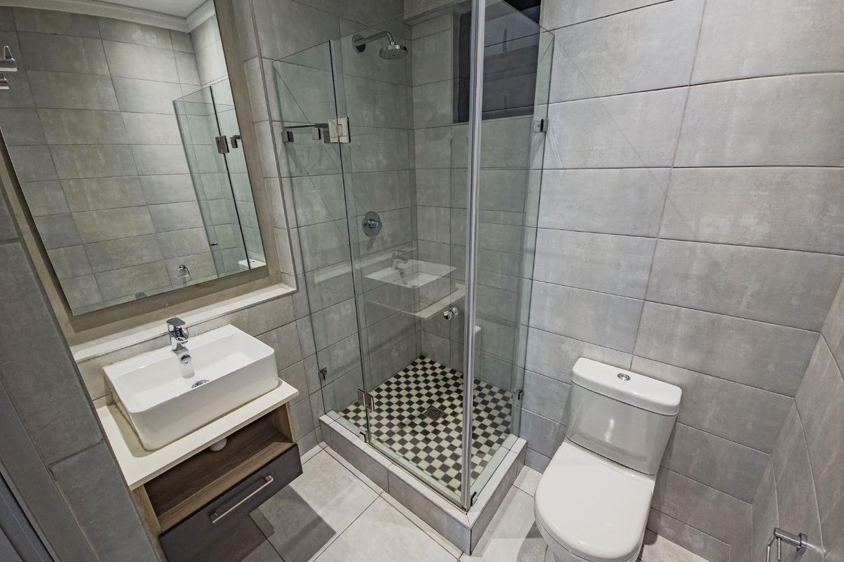 Modern bathroom featuring a glass-enclosed shower with mosaic floor tiles, a contemporary vessel sink vanity, and a wall-mounted toilet.