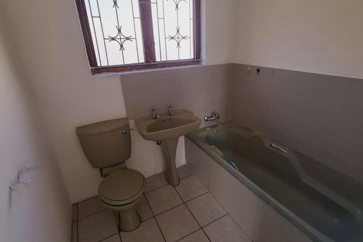 A dated bathroom featuring a pedestal basin, toilet, and bathtub with tiled flooring and wall surrounds, ready for modernization.