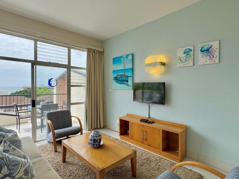 A bright living room featuring large sliding glass doors that open onto a balcony, providing natural light and access to outdoor space.