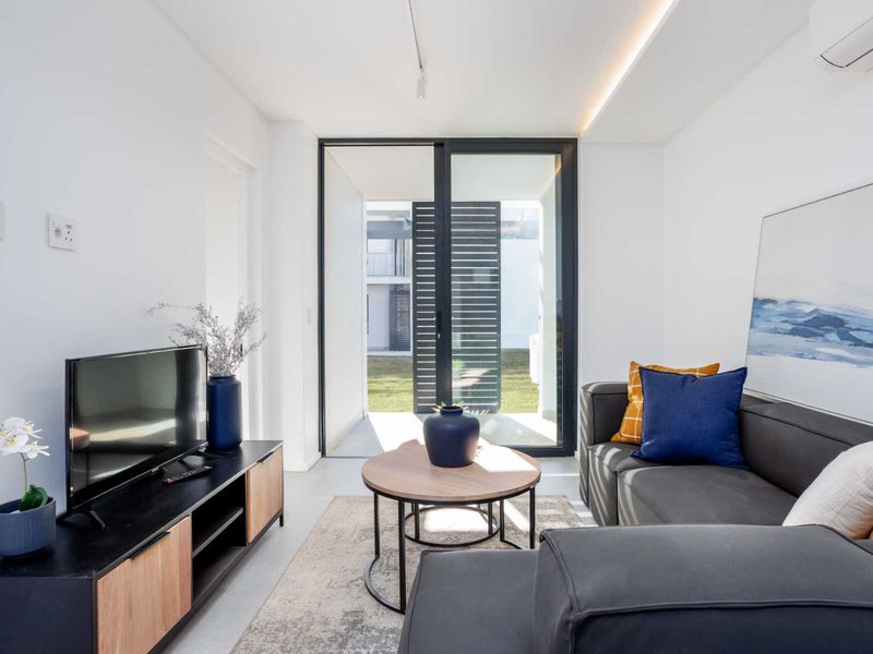 Modern living room featuring polished concrete floors, recessed lighting, and a large sliding glass door providing direct access to the outdoor area.