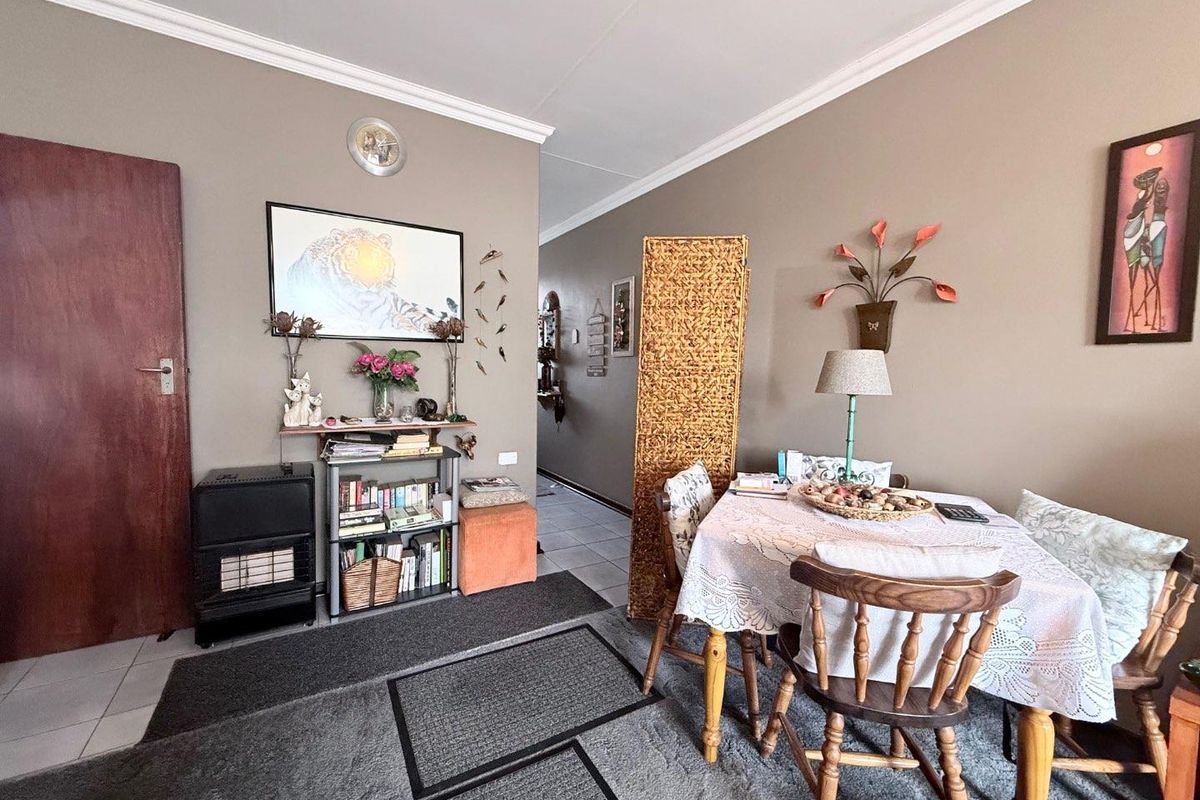 A living and dining area featuring tiled flooring, crown molding, and a neutral wall finish, providing a functional space for daily living.