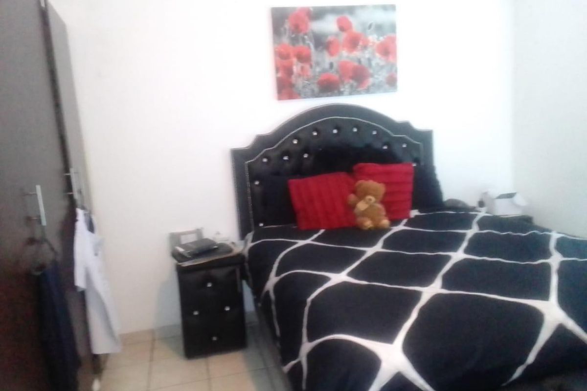 A bedroom featuring tiled flooring and a built-in wardrobe, providing functional storage space.