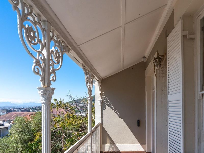 A covered balcony featuring decorative wrought iron columns and shuttered windows, offering elevated views of the surrounding neighborhood.