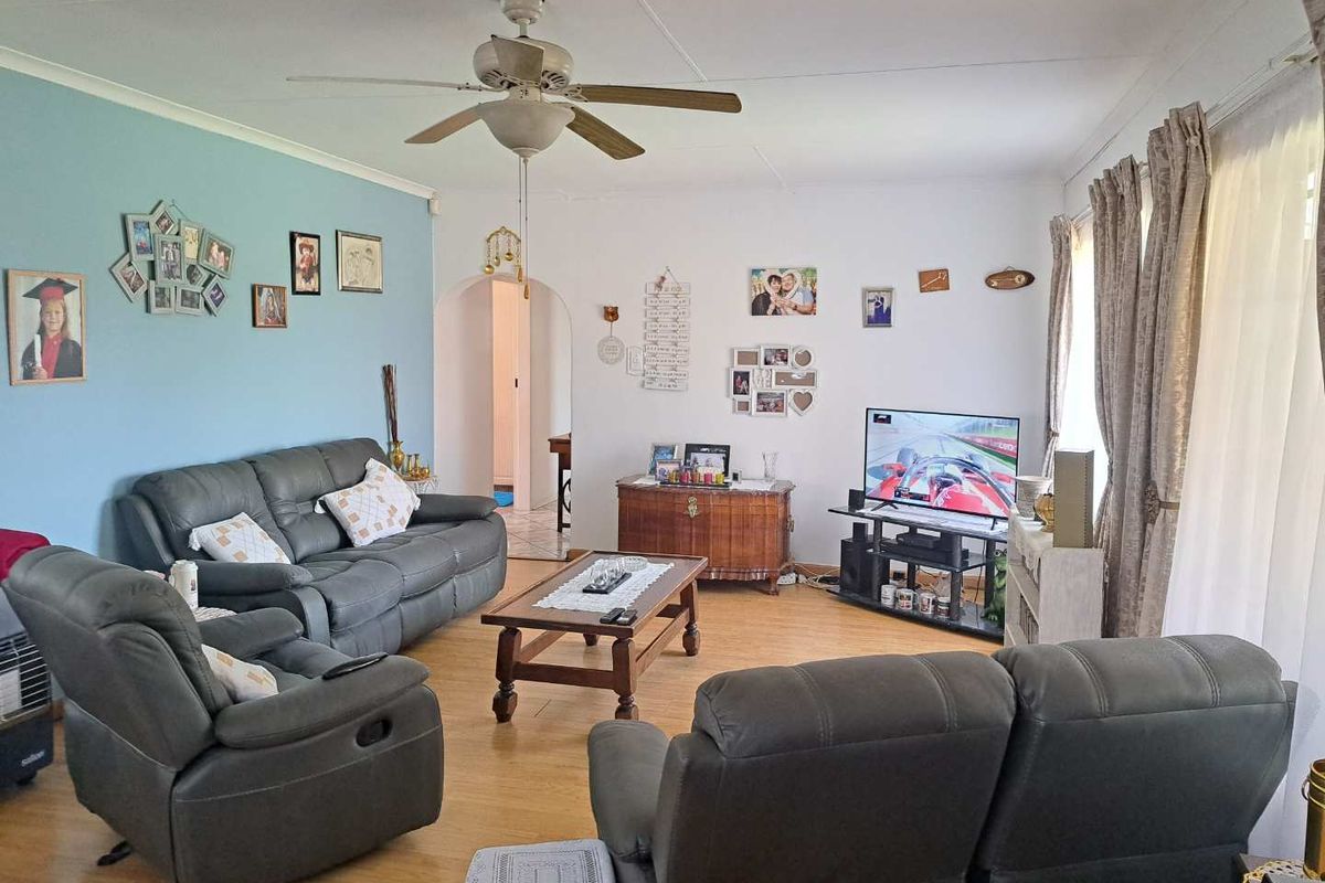 A comfortable living room featuring light wood-look flooring, a ceiling fan, and an arched doorway leading to the rest of the home.