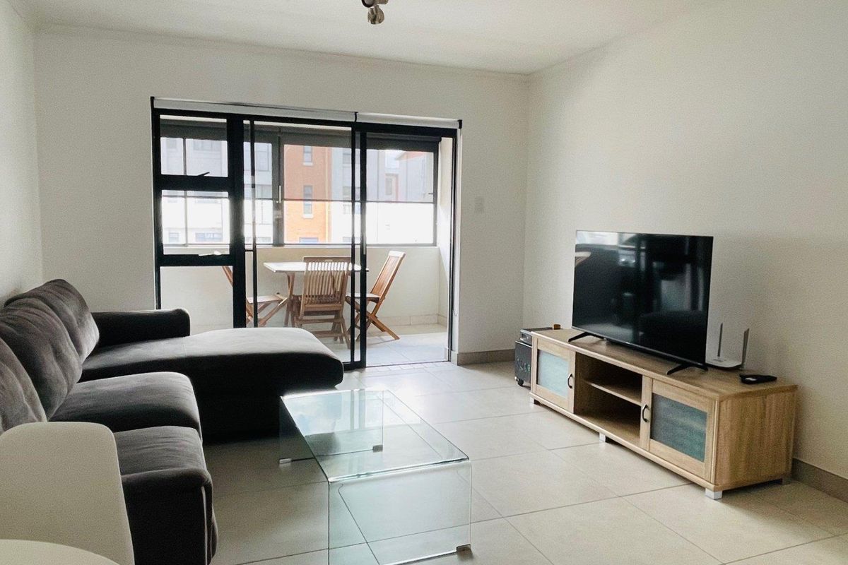 Open-plan living area featuring tiled flooring and large sliding glass doors providing access to a private balcony.