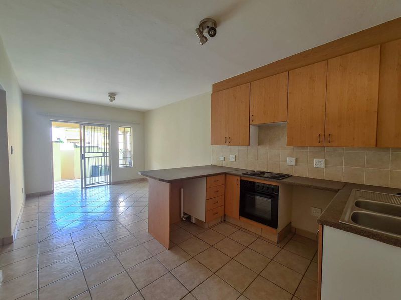 Open plan kitchen and living area featuring tiled floors, built-in cabinetry, and direct access to an outdoor patio through a sliding glass door.
