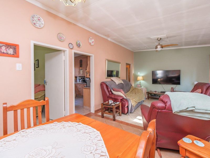 Open plan living and dining area featuring tiled flooring and a ceiling fan, with direct access to the kitchen and adjacent rooms.
