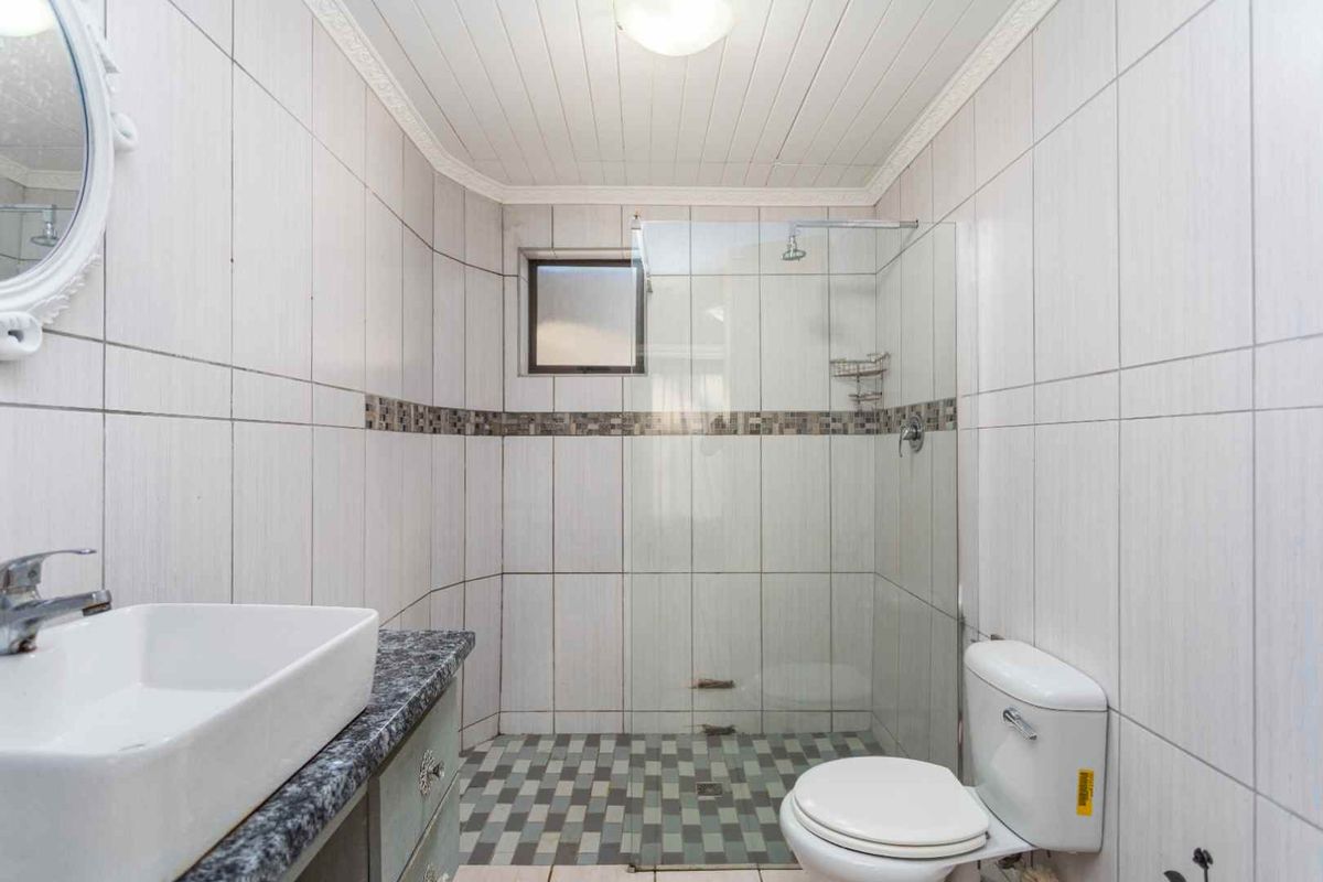 A functional bathroom featuring a glass-enclosed shower, tiled walls, a vanity with a basin, and a standard toilet.