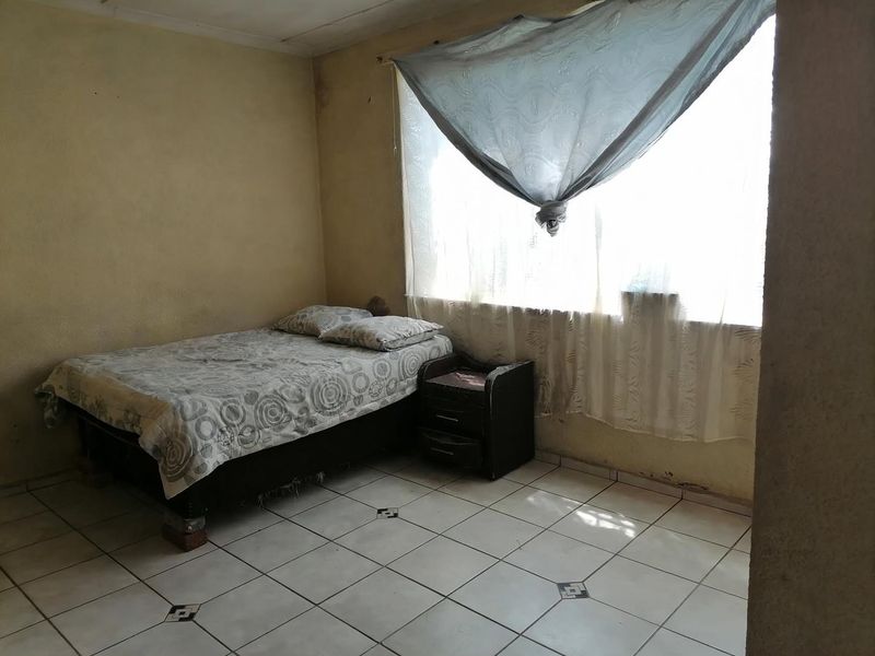 A bedroom featuring tiled flooring and plain walls, currently requiring cosmetic updates and maintenance to improve the overall condition of the space.