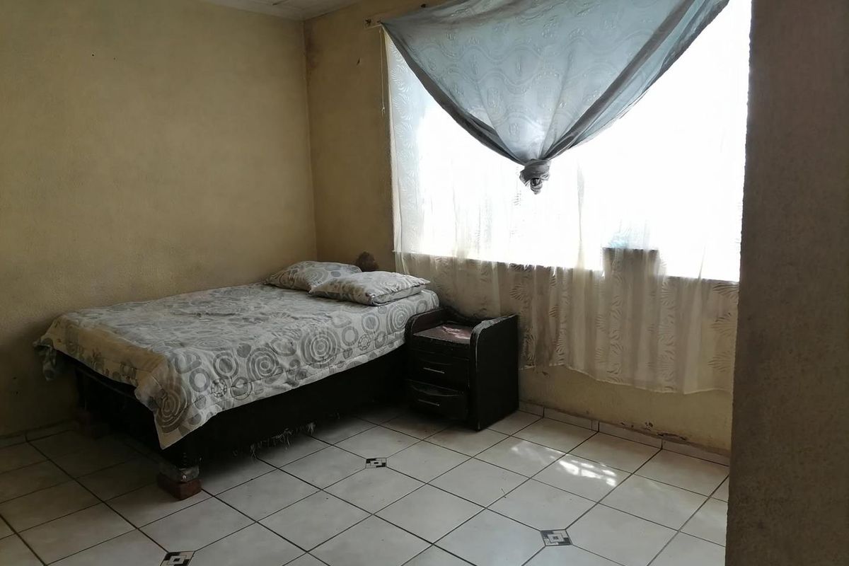A bedroom featuring tiled flooring and plain walls, currently requiring cosmetic updates and maintenance to improve the overall condition of the space.