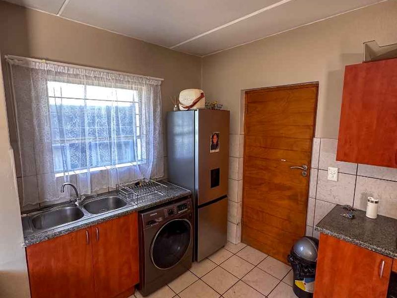 A functional kitchen featuring laminate cabinetry, granite countertops, double sink, and tiled flooring, providing a practical workspace with standard utility fixtures.