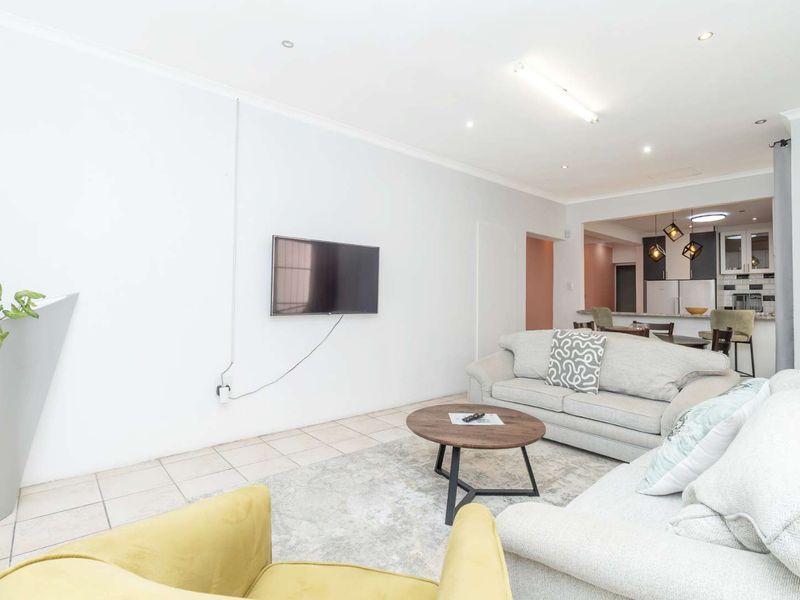Open-plan living area featuring tiled floors, recessed lighting, and a connected kitchen with cabinetry and island, offering a functional and bright living space.