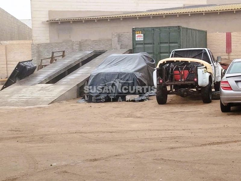Industrial yard area featuring a concrete loading ramp and perimeter masonry walling, suitable for heavy vehicle access and storage.