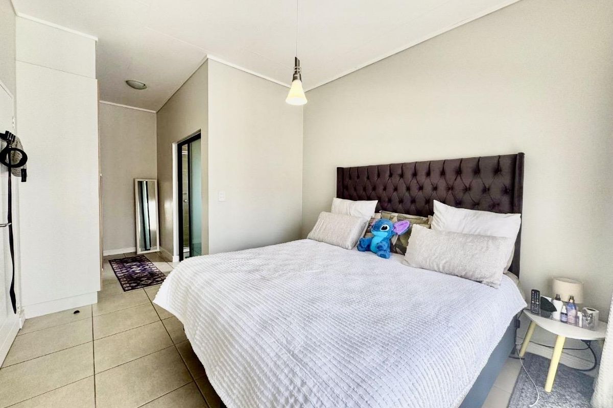 A well-lit bedroom featuring neutral tiled flooring, built-in cabinetry, and an en-suite bathroom entrance.