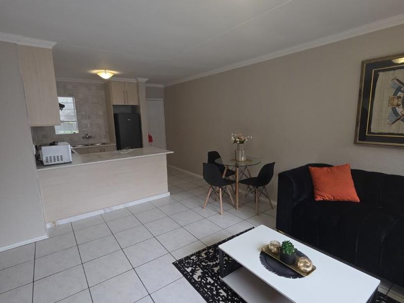 Open-plan living and kitchen area featuring tiled flooring, a breakfast bar, and neutral wall finishes, providing a functional and connected living space.