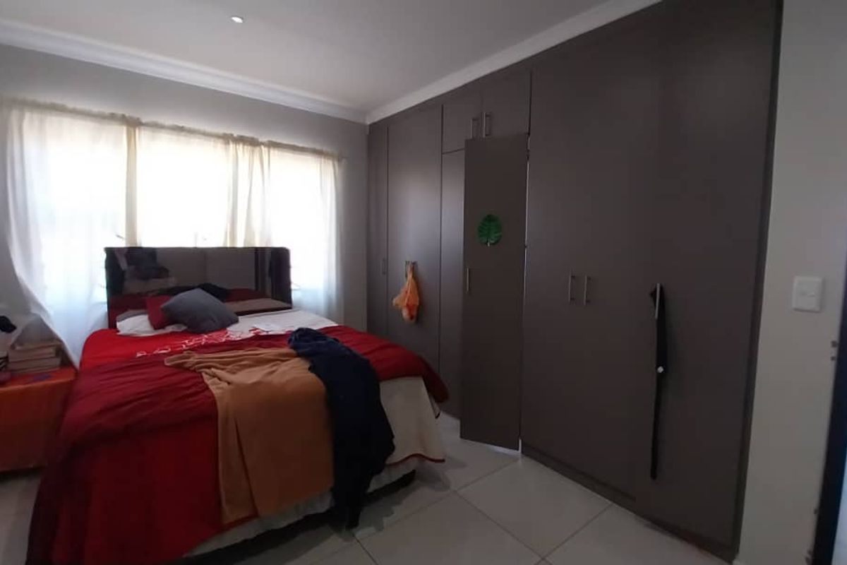 A bedroom featuring built-in floor-to-ceiling wardrobes and tiled flooring, offering ample storage space.