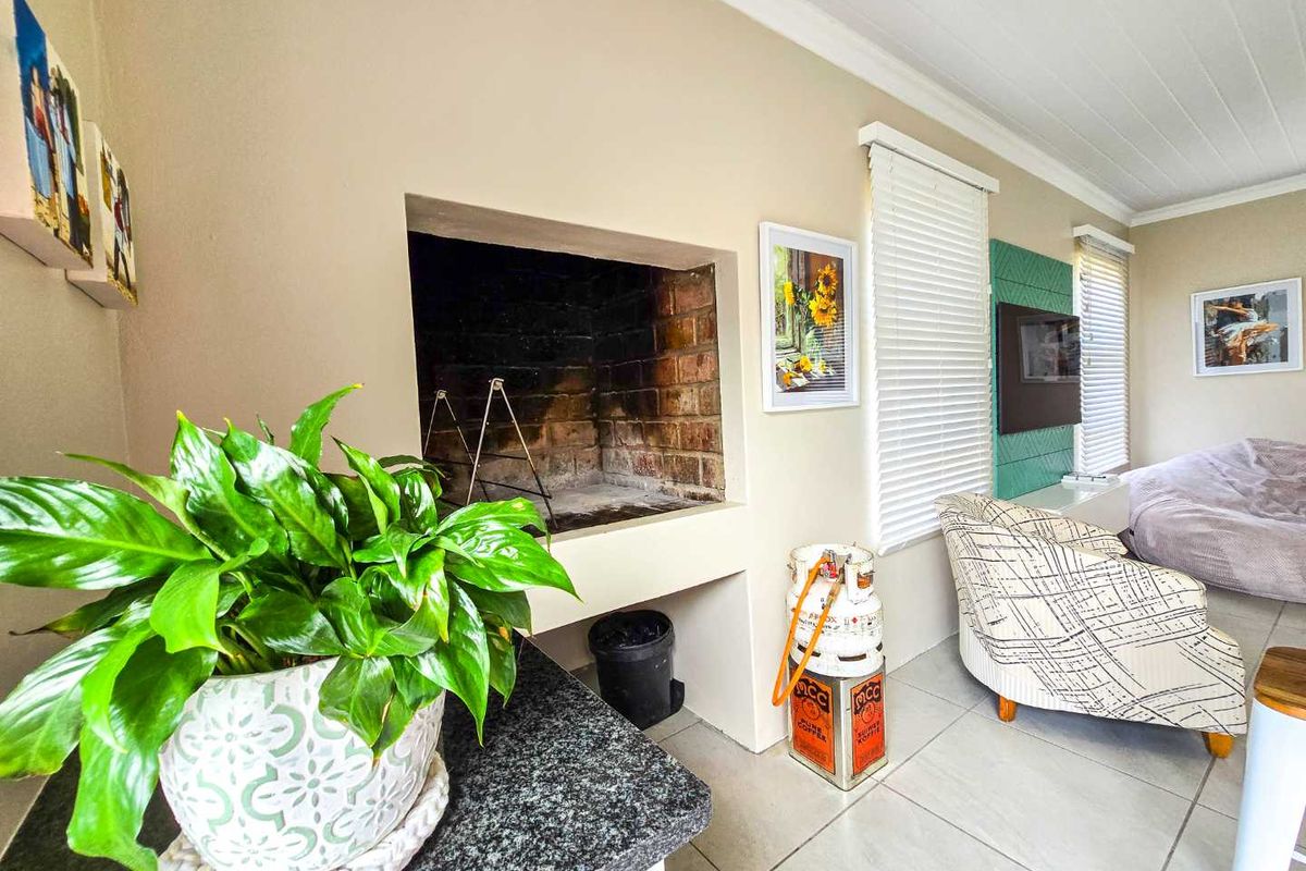 Indoor living area featuring a built-in brick fireplace, tiled flooring, and venetian blinds, creating a functional and cozy entertainment space.