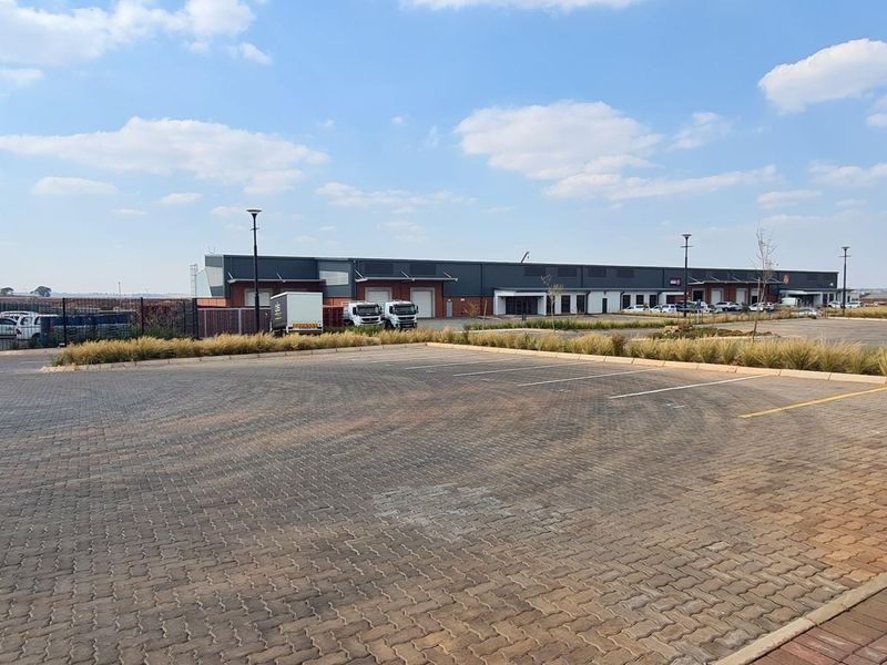 Wide-angle view of an industrial property featuring a large paved parking area, loading bays, and a modern warehouse facility.