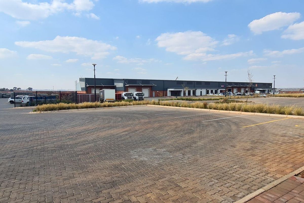 Wide-angle view of an industrial property featuring a large paved parking area, loading bays, and a modern warehouse facility.