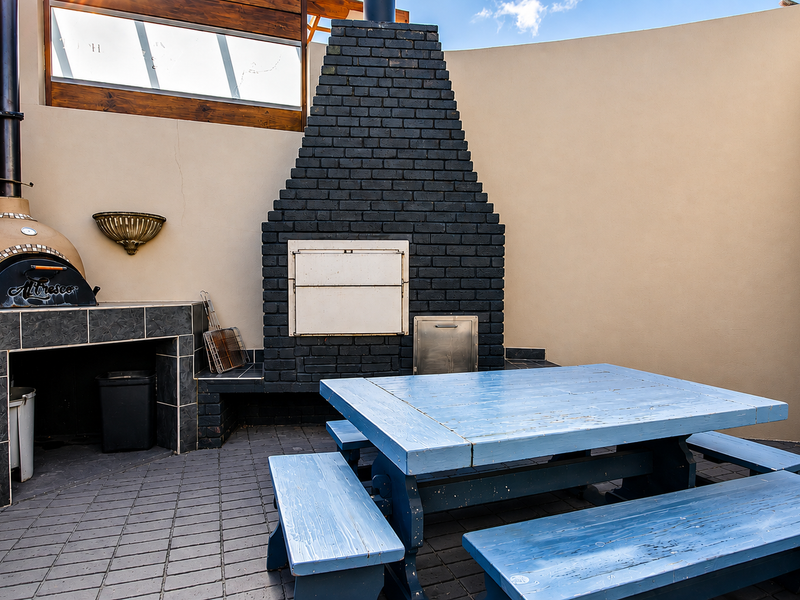 Outdoor entertainment area featuring a built-in brick fireplace, pizza oven, and paved patio flooring, ideal for alfresco dining and social gatherings.