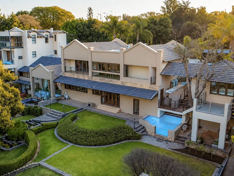 Aerial view of a large multi-level residence featuring a well-maintained landscaped garden, swimming pool, and expansive outdoor entertainment areas.