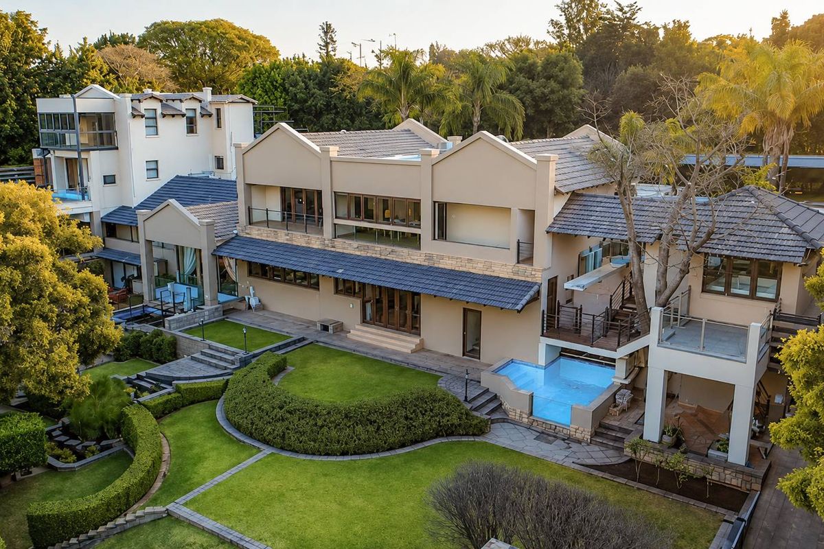 Aerial view of a large multi-level residence featuring a well-maintained landscaped garden, swimming pool, and expansive outdoor entertainment areas.