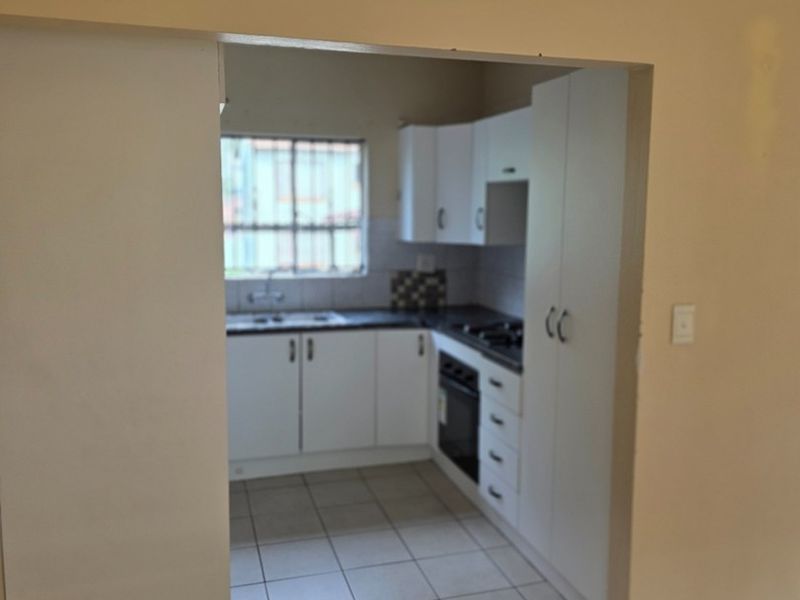 A compact, functional kitchen featuring white built-in cabinetry, laminate countertops, a built-in oven, and tiled flooring.