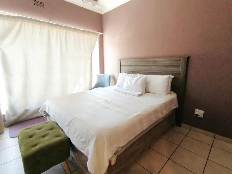 A bedroom featuring tiled flooring and a ceiling vent, with neutral wall tones and natural light from the window.