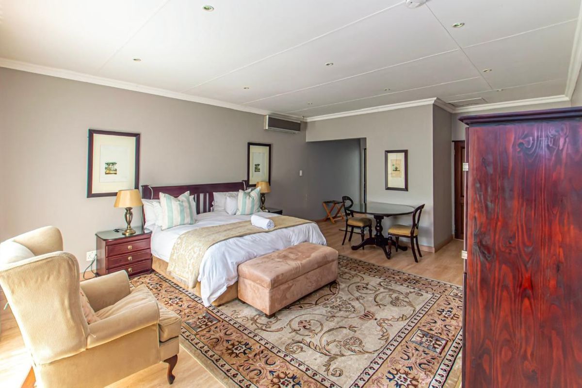 Spacious bedroom featuring light wood-look flooring, recessed ceiling lighting, and a wall-mounted air conditioning unit.