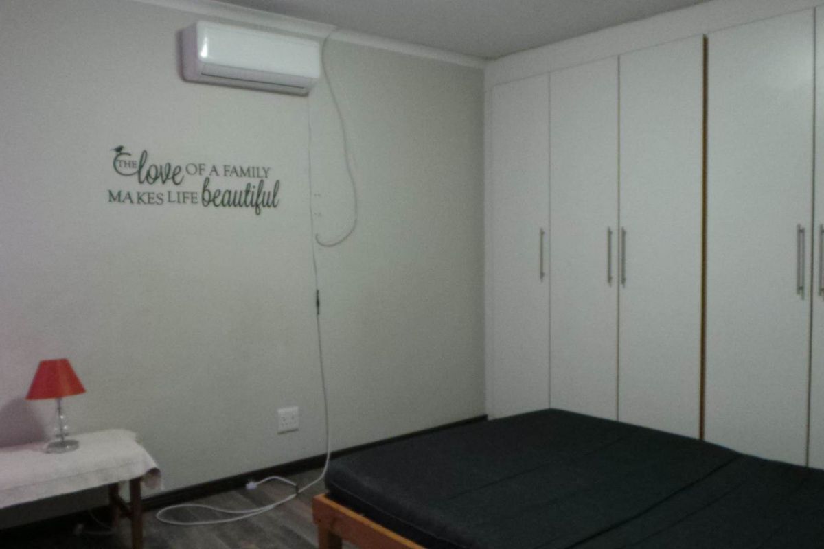 A bedroom featuring built-in floor-to-ceiling wardrobes and a wall-mounted air conditioning unit.
