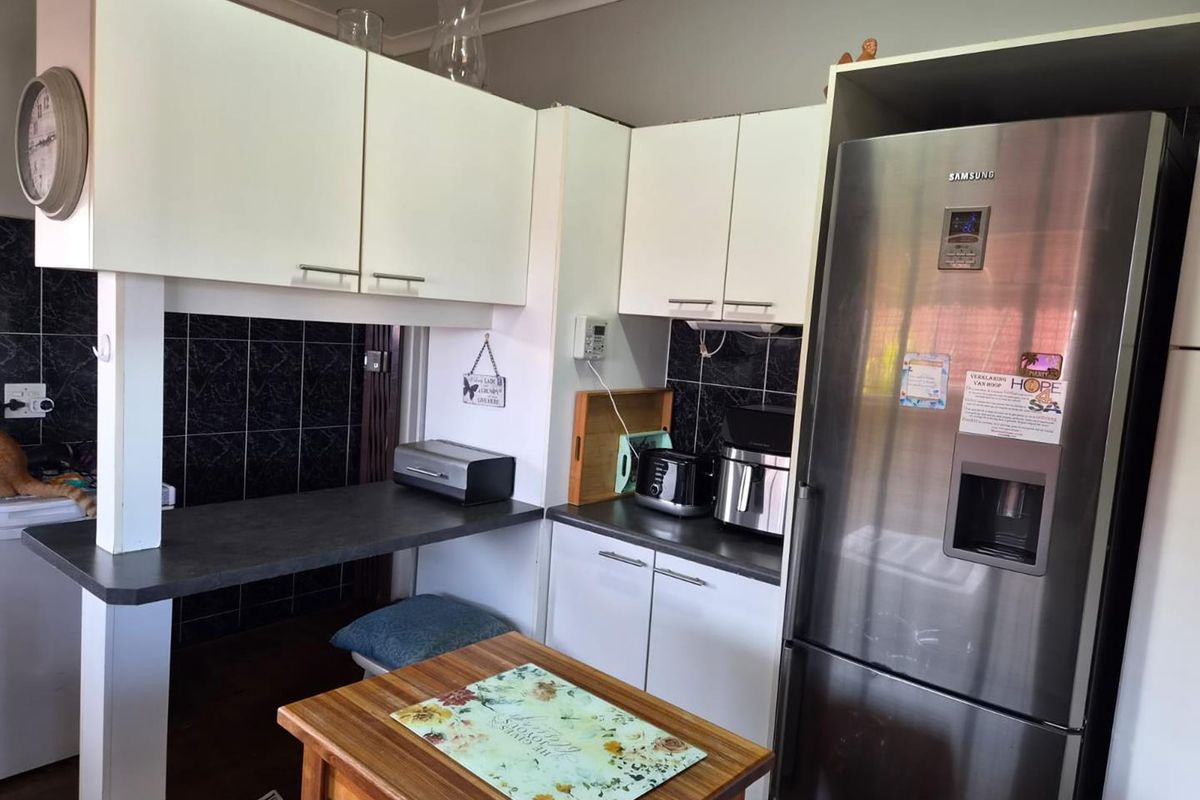 A functional kitchen featuring white built-in cabinetry, dark laminate countertops, and a black tiled backsplash.