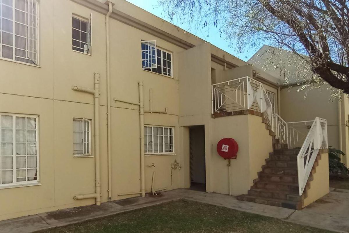 Exterior view of a townhouse complex featuring a staircase leading to an upper level, metal railings, and standard window frames.