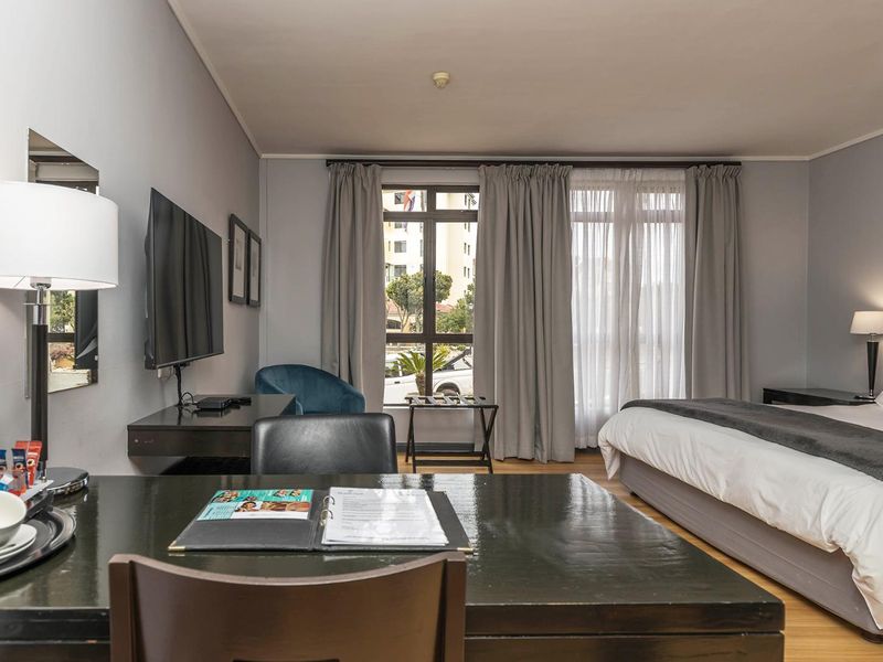 A well-maintained bedroom featuring laminate flooring and large windows with curtain tracks, offering a functional and comfortable living space.