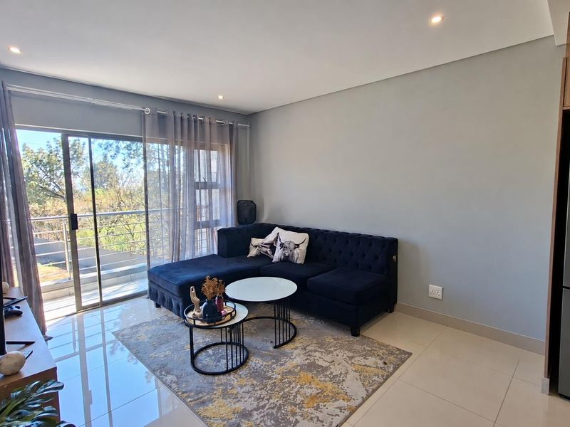 Modern open-plan living area featuring tiled floors, recessed lighting, and a large sliding glass door providing access to the balcony.