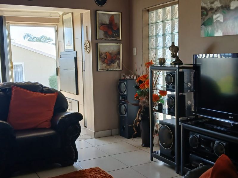 A living room featuring tiled flooring, a glass block feature window, and a sliding door providing access to an outdoor area.