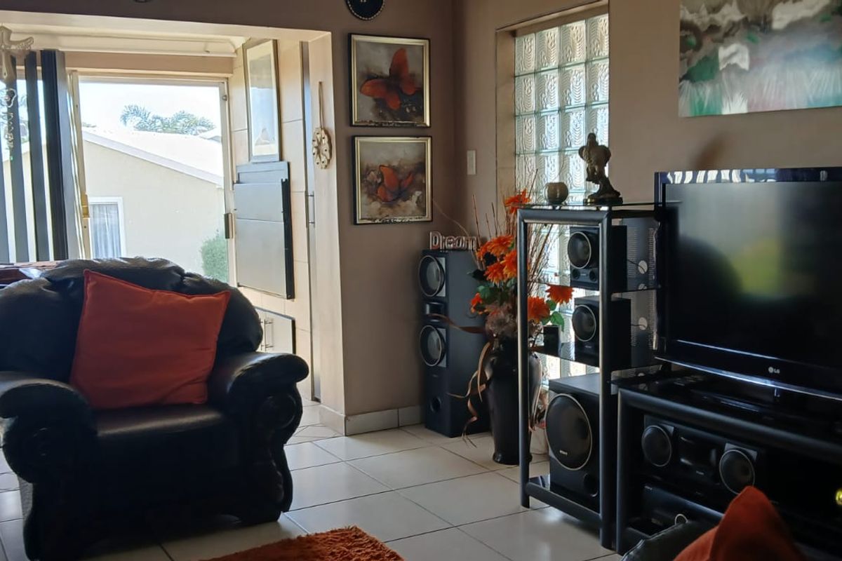 A living room featuring tiled flooring, a glass block feature window, and a sliding door providing access to an outdoor area.