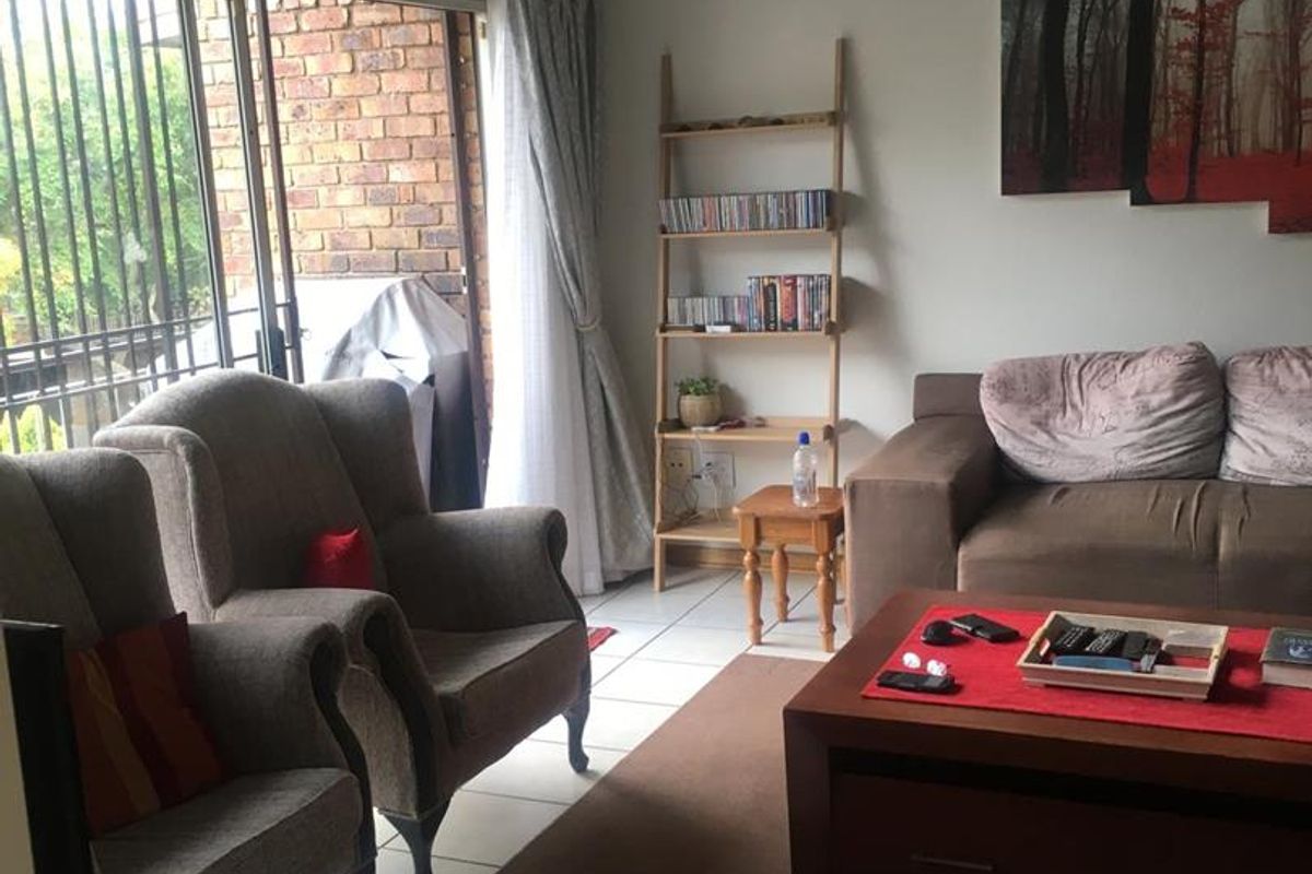 A living room featuring tiled flooring and large sliding glass doors that provide access to an outdoor patio area.