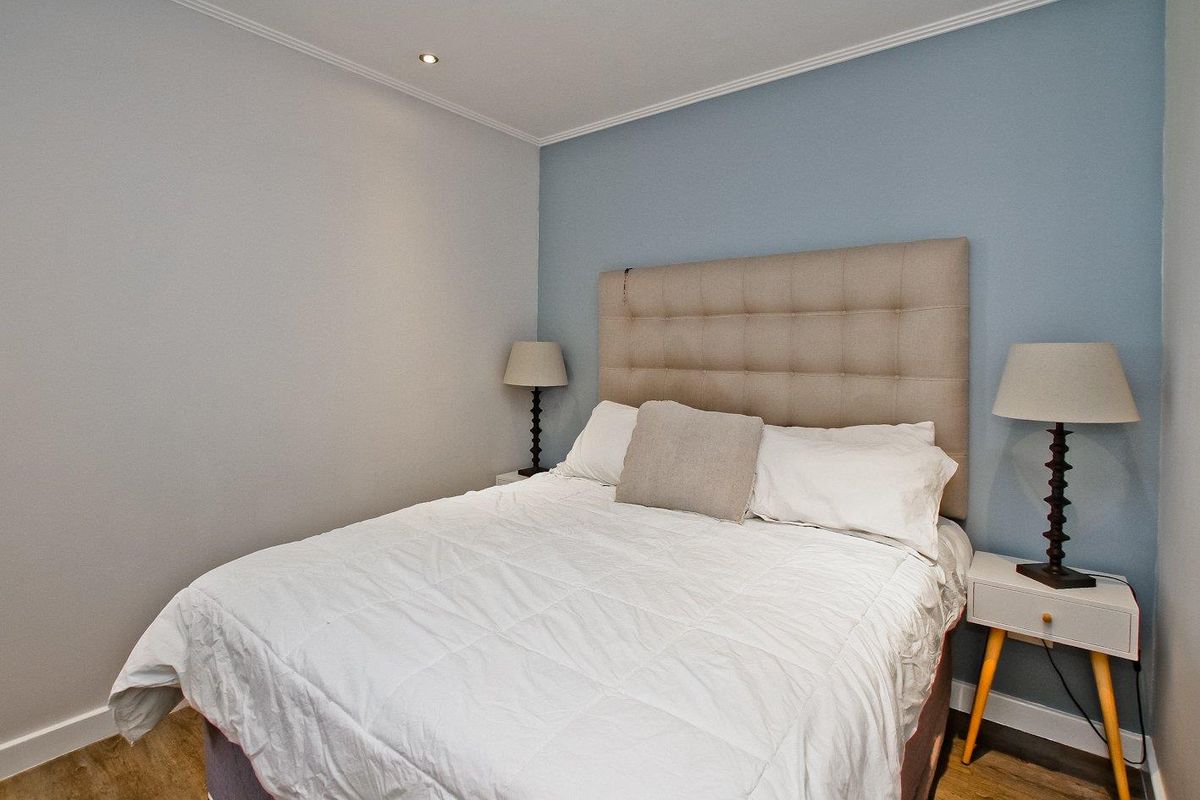 A well-maintained bedroom featuring recessed ceiling lighting, crown molding, and wood-look flooring.