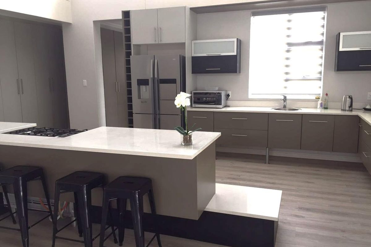 Modern kitchen featuring a central island with a built-in gas hob, sleek cabinetry, stone countertops, and integrated storage solutions.