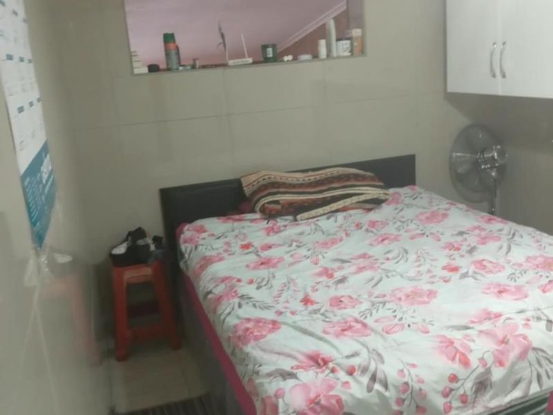 A compact bedroom featuring tiled walls, built-in cabinetry, and a ceiling fan. The space requires minor maintenance to address exposed wiring.